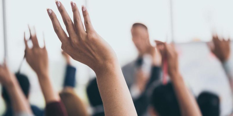 imagem com mãos levantadas de pessoas votando em uma assembléia