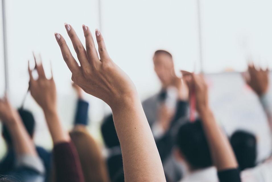 imagem com mãos levantadas de pessoas votando em uma assembléia